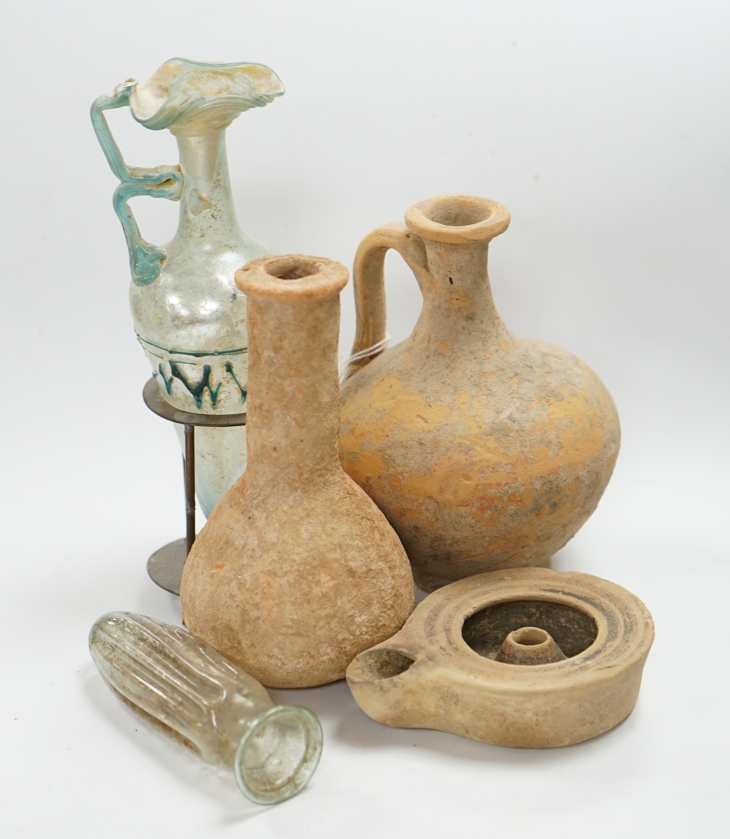 A Roman glass vase on stand, a similar Roman glass vase and three terracotta Syrian style vessels, tallest Roman vase on stand 17cm high (not including stand). Condition - Roman vase on stand cracked at neck, other vase